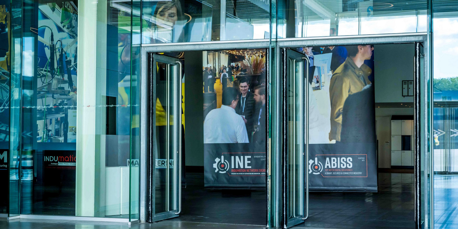 Glaseingang mit Bannern für INE- und ABISS-Veranstaltungen.