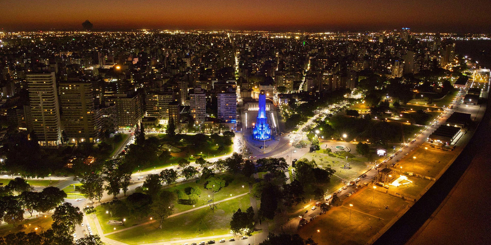 Aerial night view of Rosario city center with the illuminated National Flag Memorial and surrounding parkland.