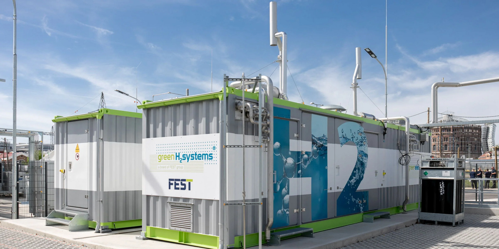 Modular hydrogen production facility from greenH2systems and FEST in an industrial area under a blue sky.
